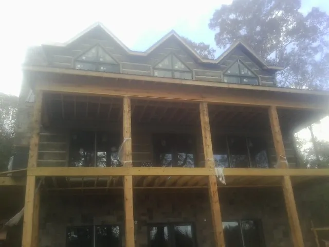 Dormers and porch framing on a large log home under construction — Roof Coating work by our crew in Pershing