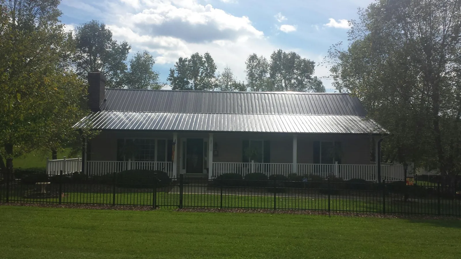 Gray metal roof on a brick ranch with a full width front porch — Gutter Guard Installation work by our crew in Pershing