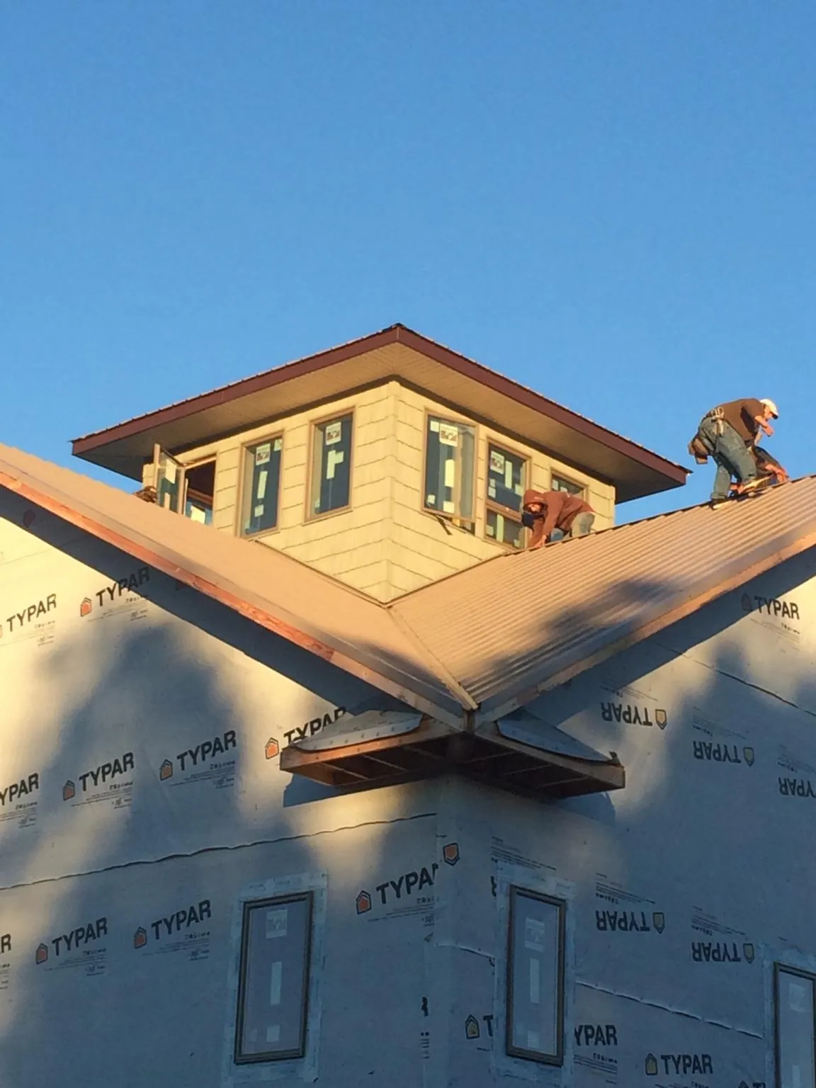 Roofers working around a rooftop cupola on a new metal roof at sunset — Roof Waterproofing in Pershing by Roofing Brothers